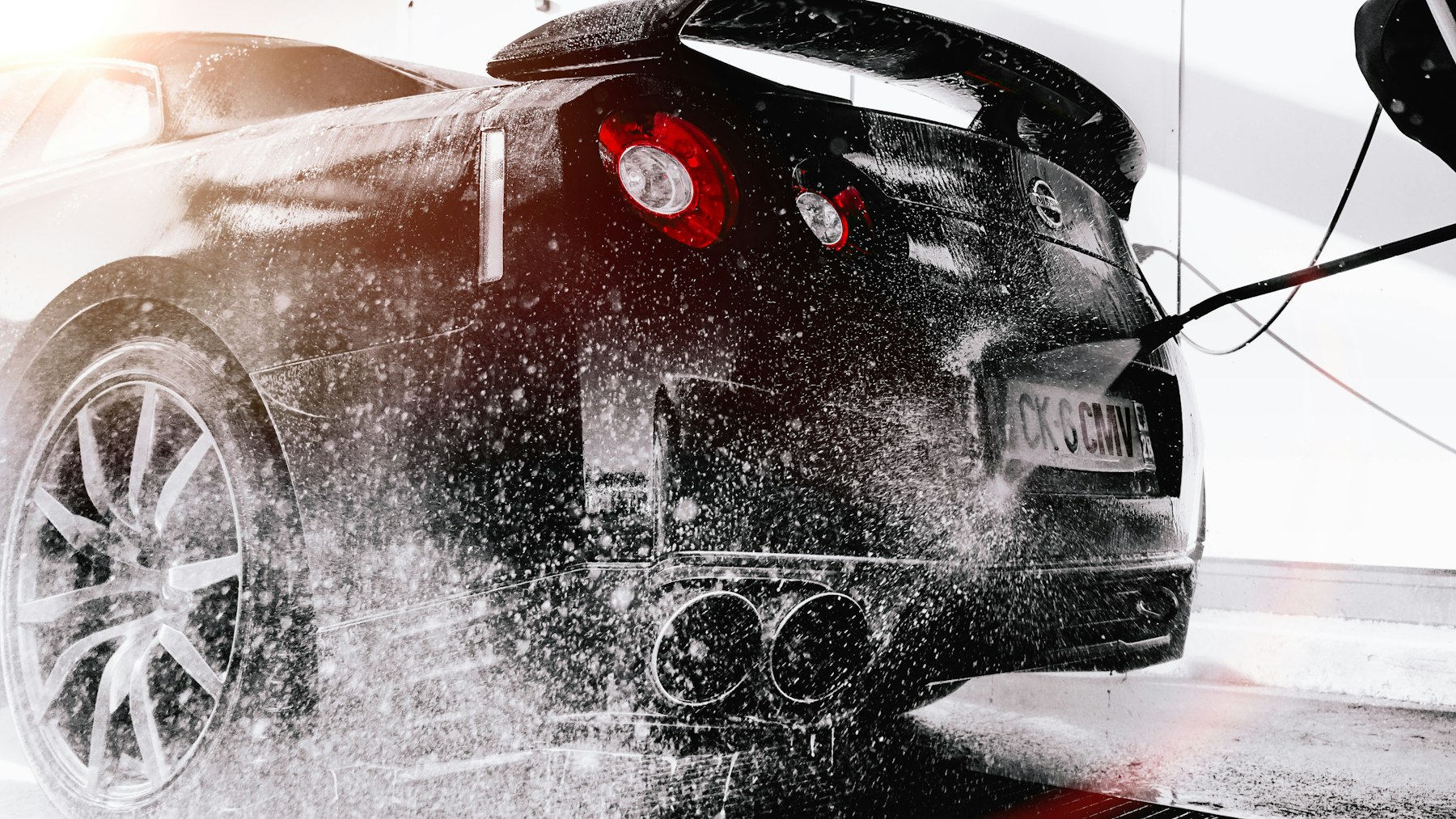A dark car being rinsed down during an exterior wash